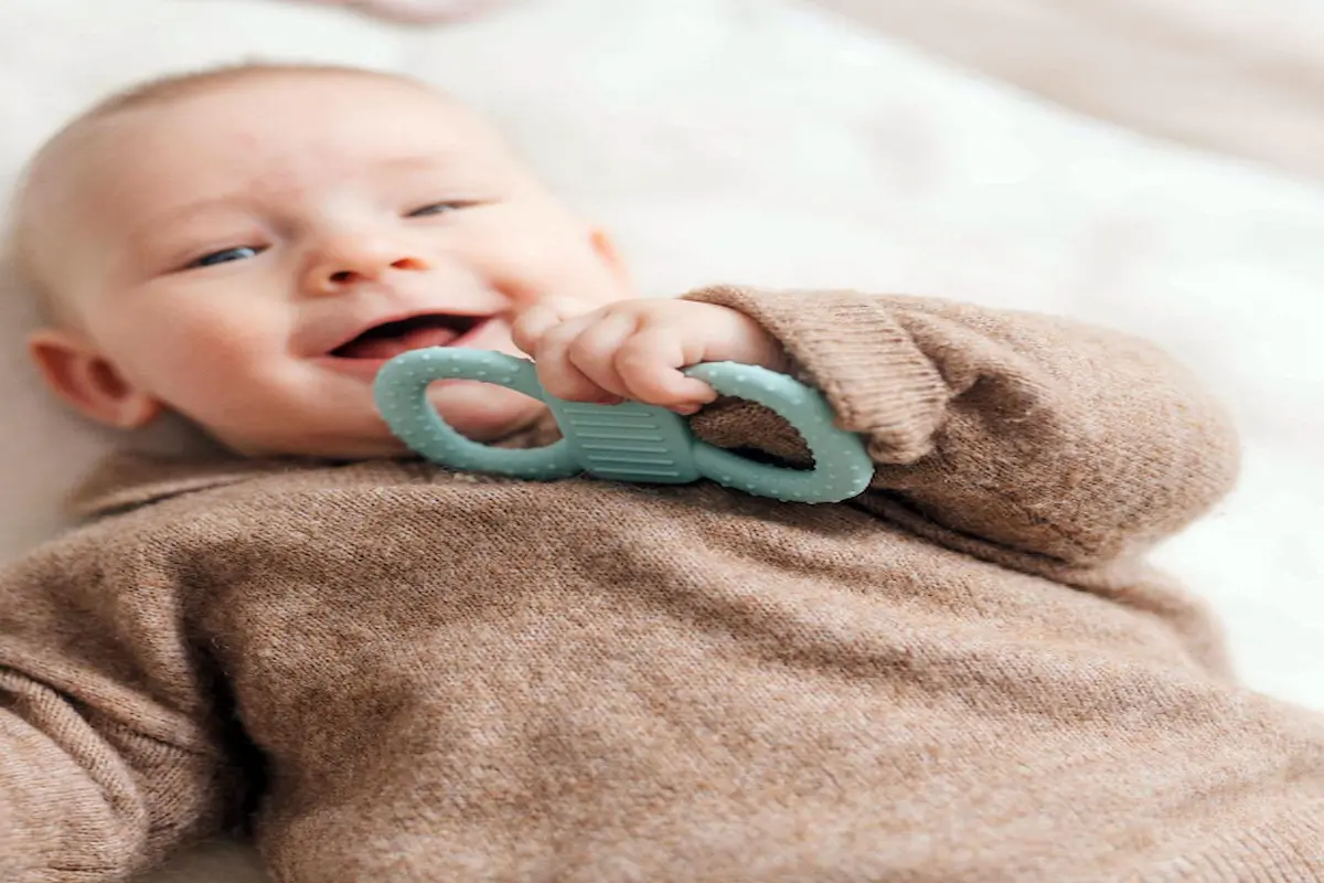 Baby hält den mimiloo Greif- und Beißring in den Händen und erkundet ihn spielerisch während der Zahnungsphase.